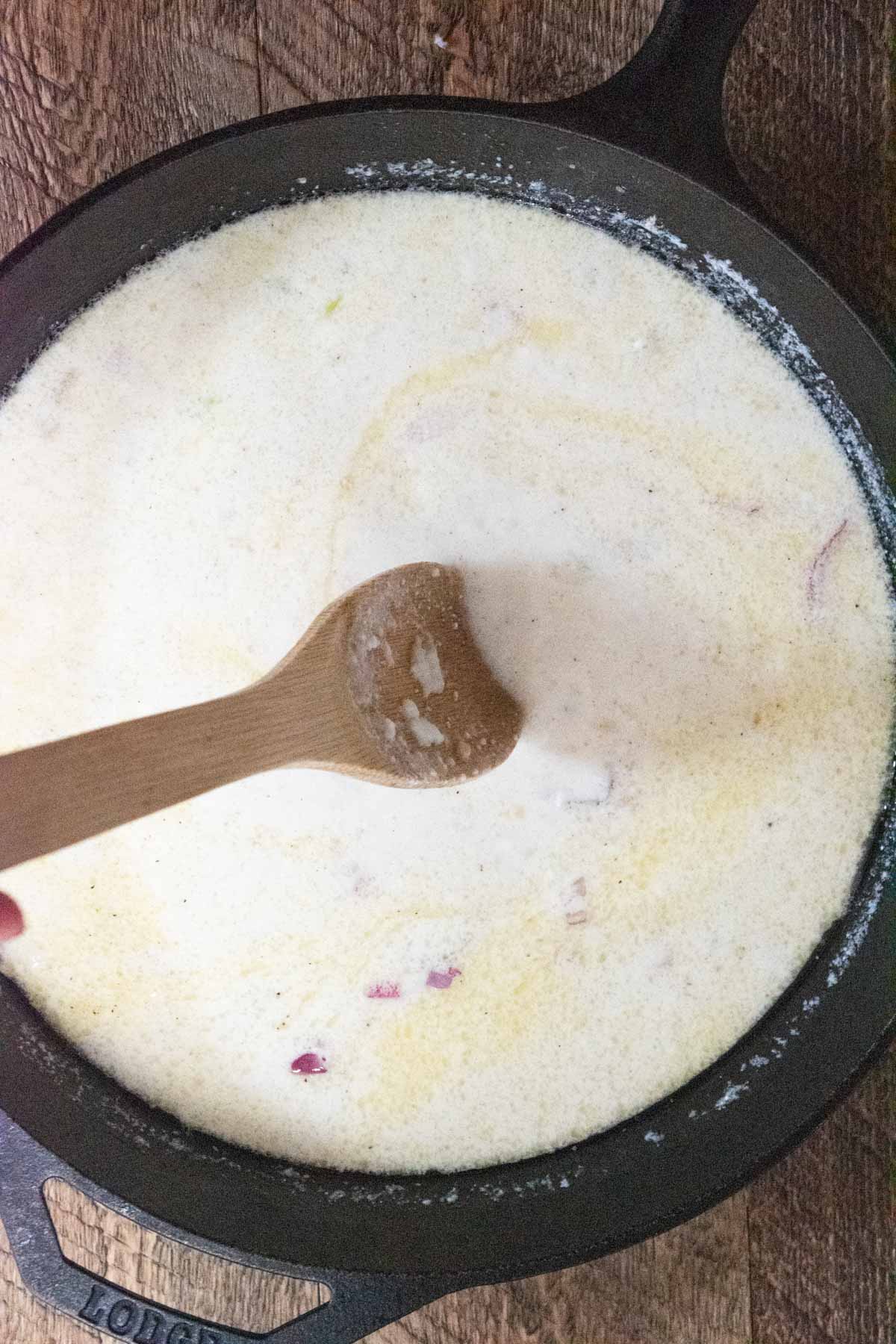 greek yogurt and coconut milk being added to the cast iron skillet 