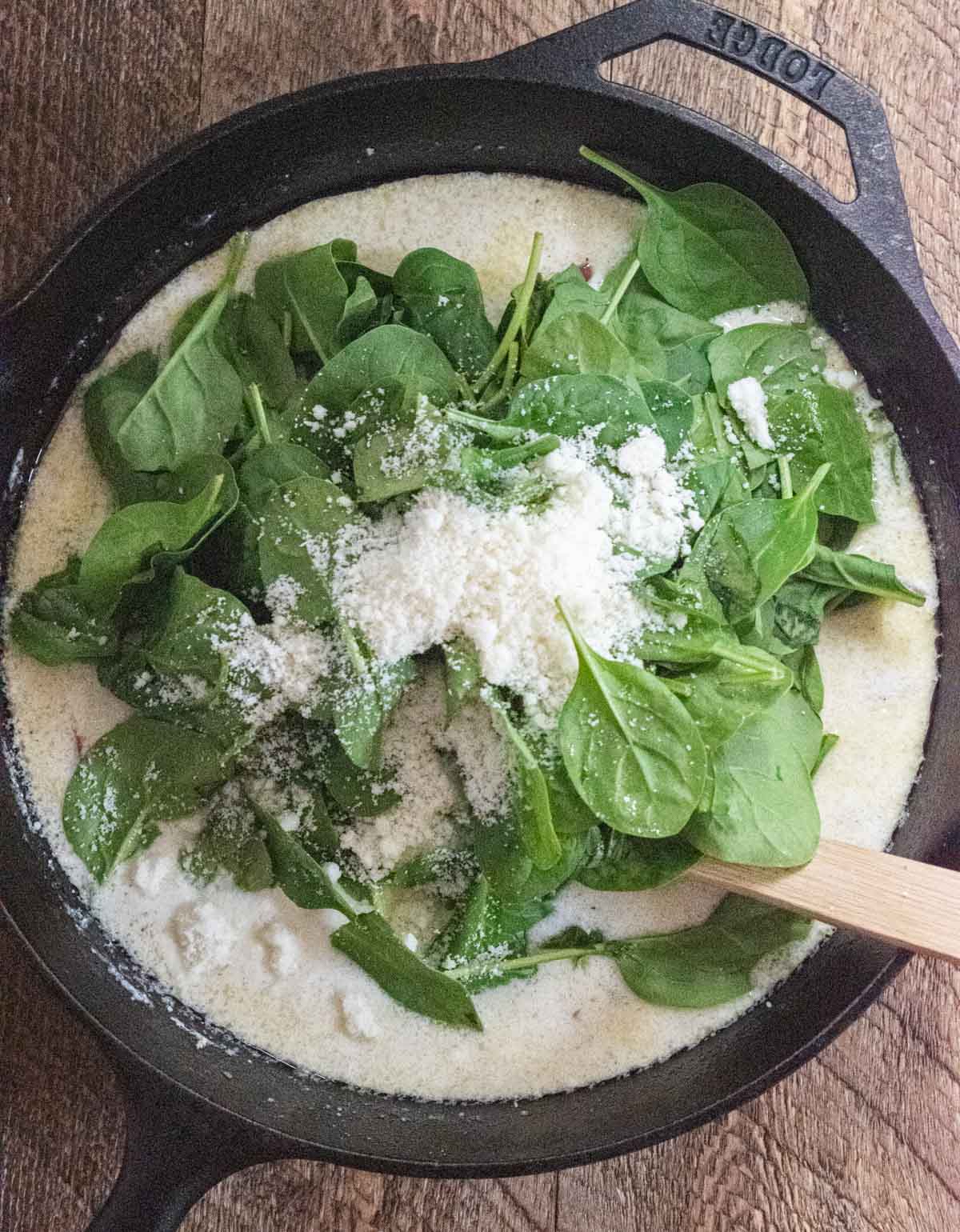 chives, spinach, lemon and cheese being added into the cast iron skillet