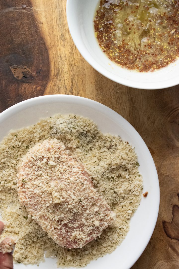 porkchops being coated in a panko mixture