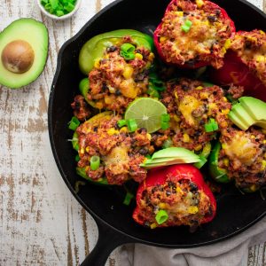 birds eye view of stuffed bell peppers with ground turkey, avocados, scallions, and limes in a cast iron skillet