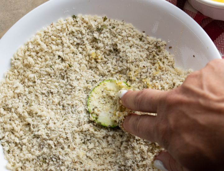 zucchini chip being dipped into panko mix