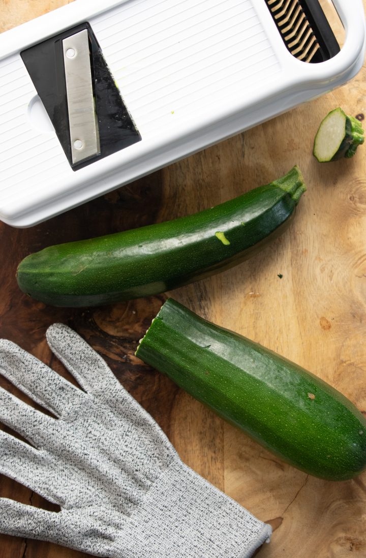 mandoline slicer, 2 zucchini, and safety glove