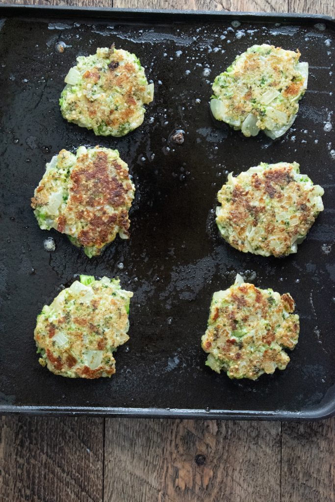 quinoa veggie patties getting crispy on a flat frying pan