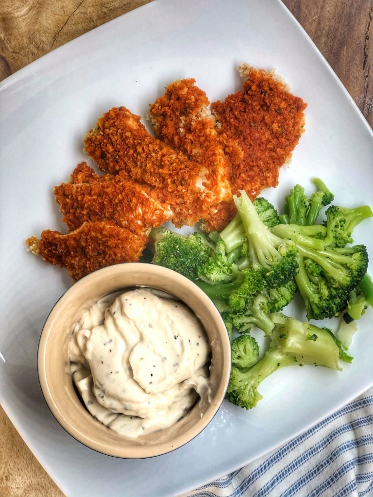 healthy baked buffalo chicken nuggets on a white plate with some broccoli and dipping sauce