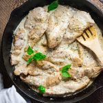 creamy chicken dijon in a cast iron skillet on a wooden board