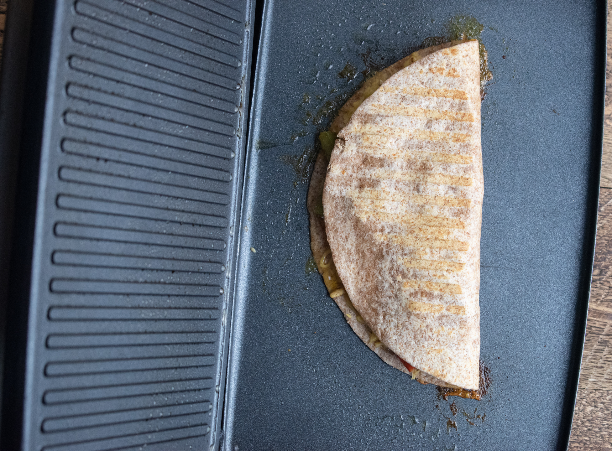 birds-eye view of a closed quesadilla on a panini press getting toasted