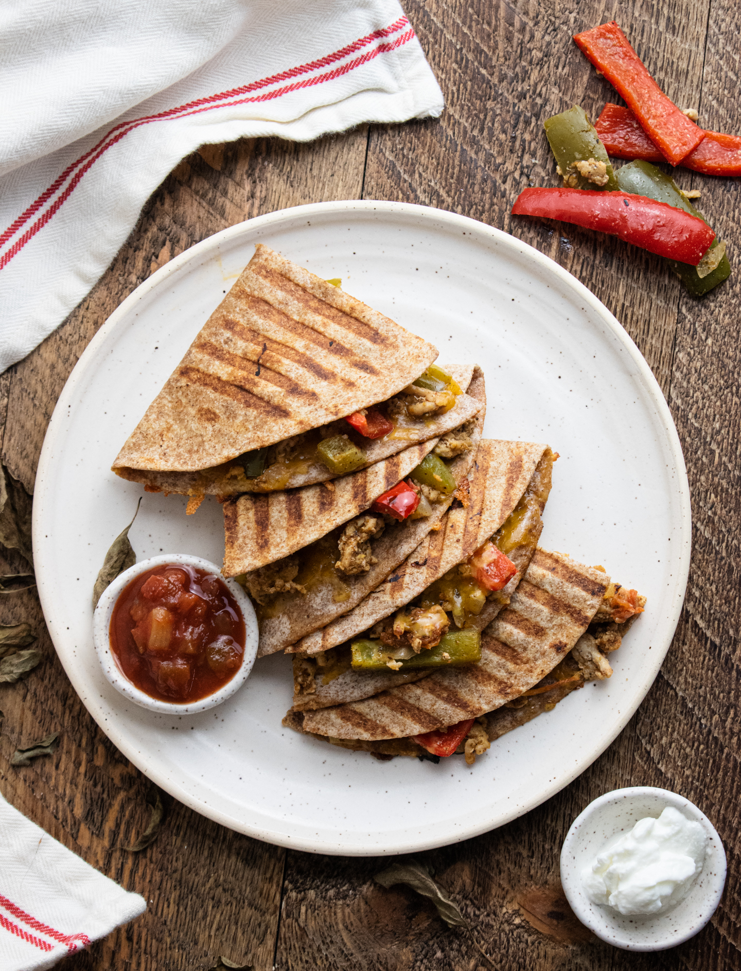 birds eye view of healthy chicken quesadillas on a white plate with salsa and plain greek yogurt for dipping 