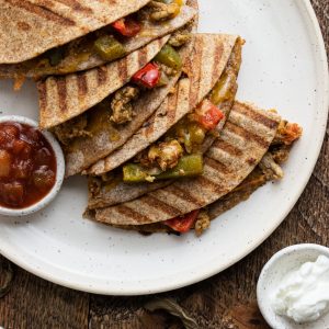 crispy healthy chicken quesadillas on a white plate with salsa and plain greek yogurt