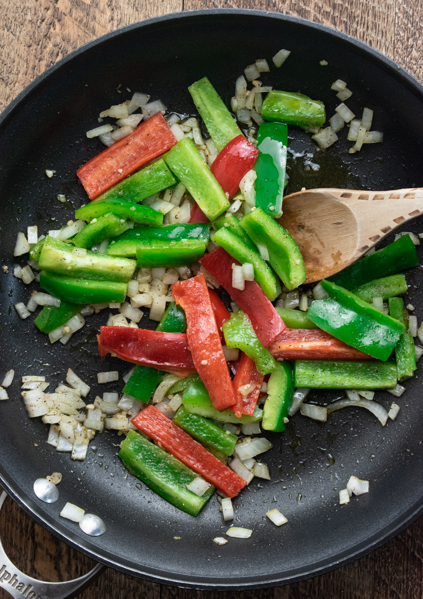 garlic, bell peppers, and onions sauting in oil to make healthy chicken quesadillas