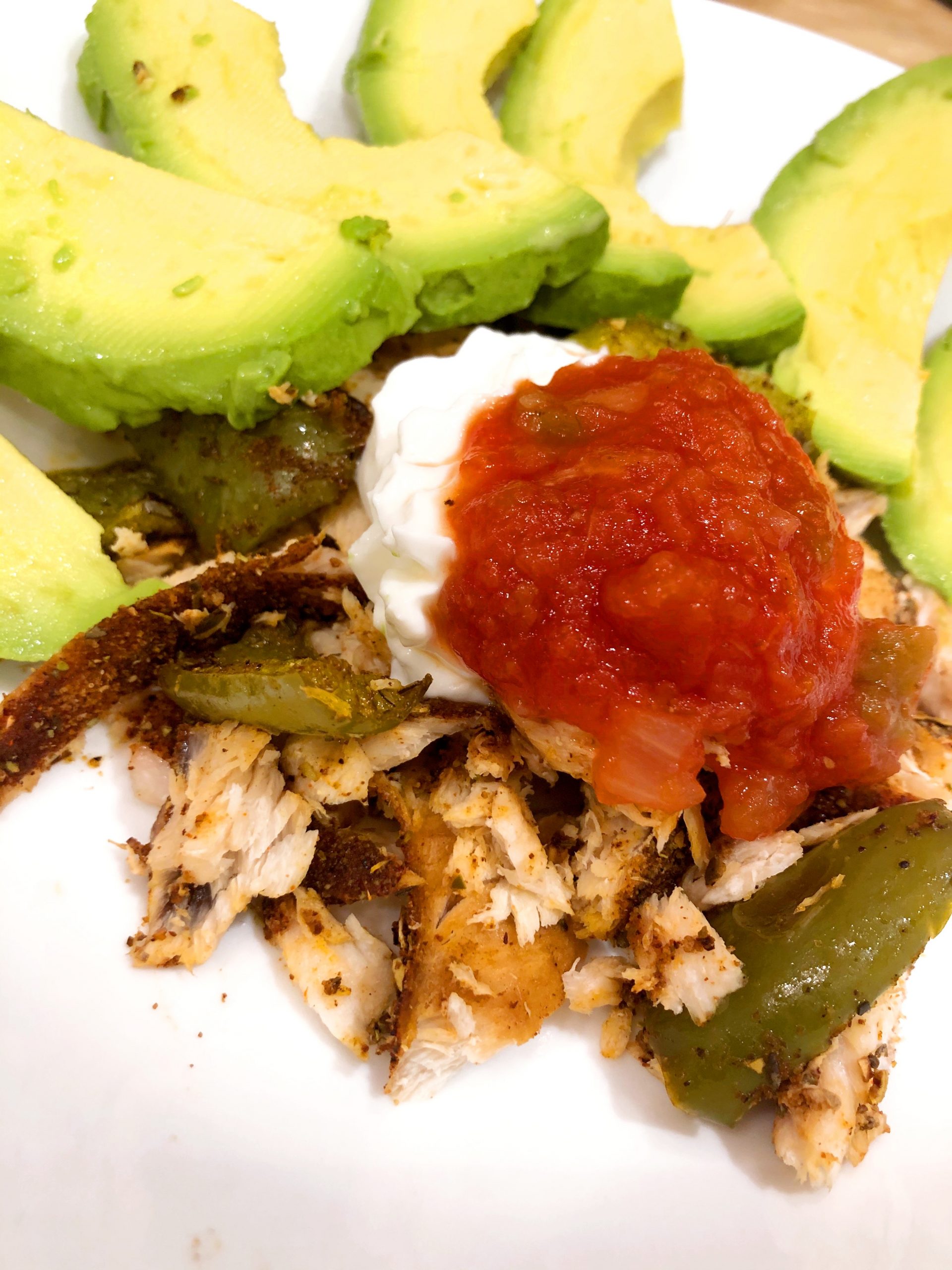 close up of fish tacos in a white bowl with green bell peppers plain greek yogurt, salsa,and avocado