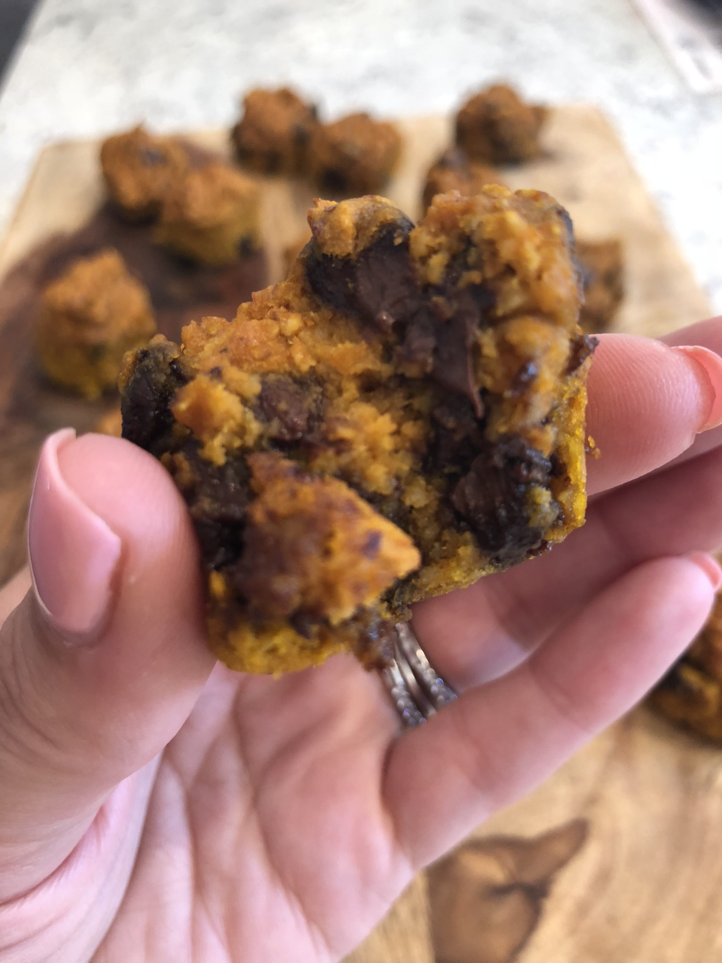 a close up of a hand holding the pumpkin oat mini muffins