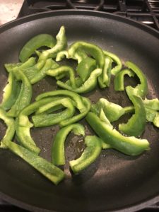 green bell peppers sauteeing in a pan