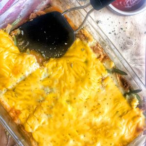 healthy cheeseburger pie in a pyrex dish with a black spatula