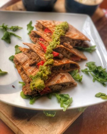close up of ground turkey quesadillas on a white plate on a wooden board