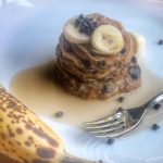 whole wheat banana chocolate chip pancakes with a silver spoon on a white plate