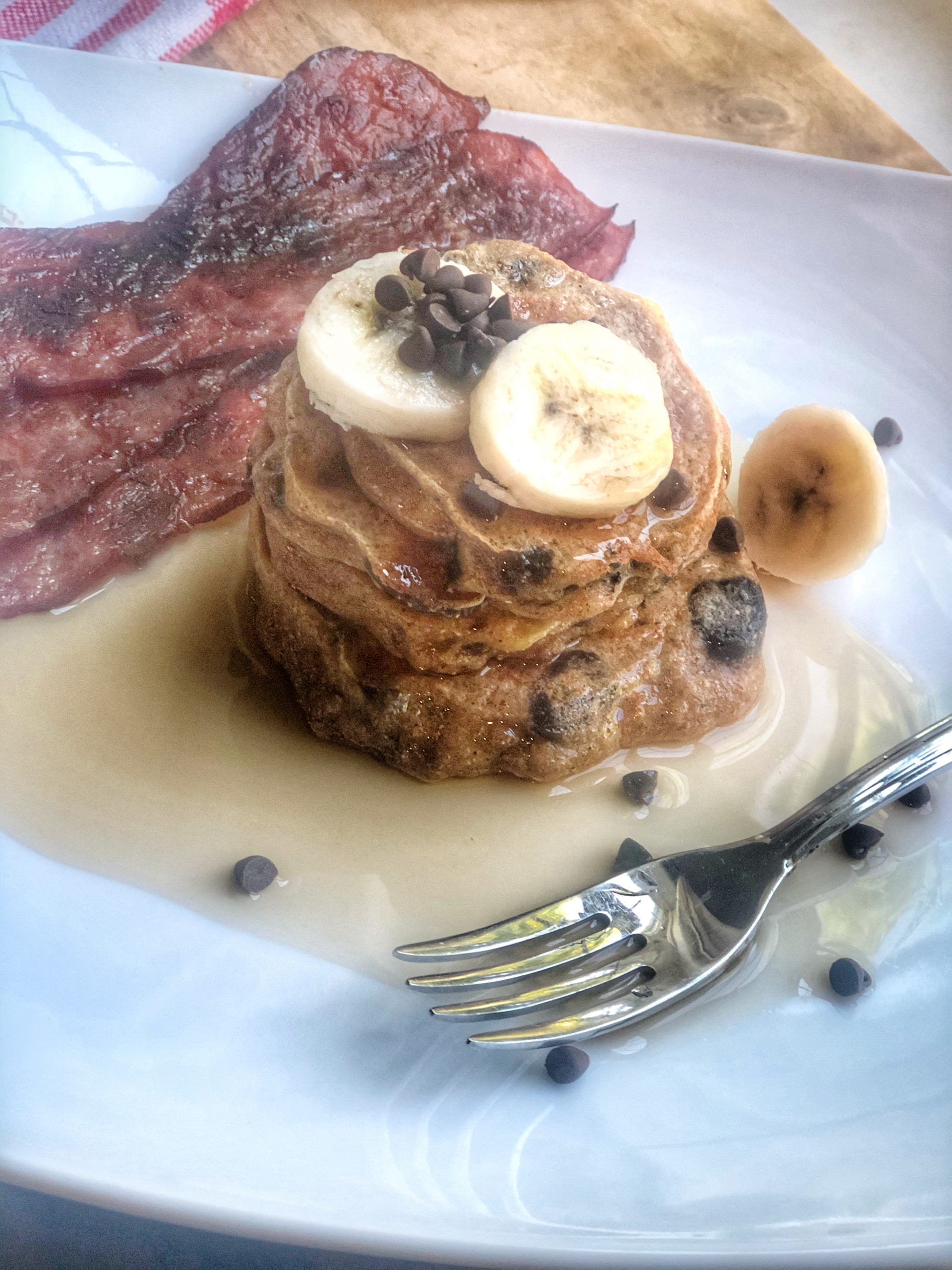 close up of whole wheat banana chocolate chip pancakes on a white plate