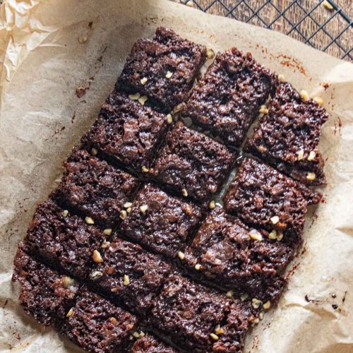 birds eye view of gluten free dairy free brownies on parchment paper on top of a wooden table with a glass of milk