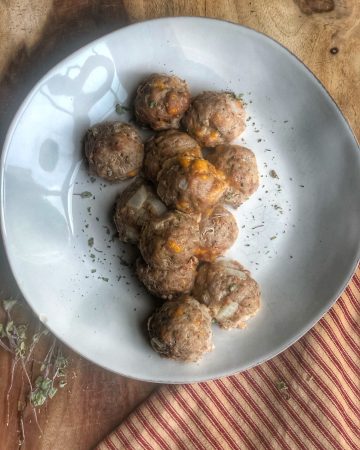 ground turkey cheesy meatballs on a white plate on a wooden board with a red and white striped napkin