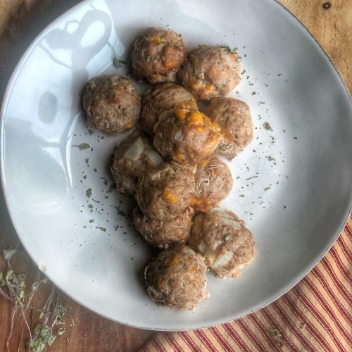 ground turkey cheesy meatballs on a white plate on a wooden board with a red and white striped napkin