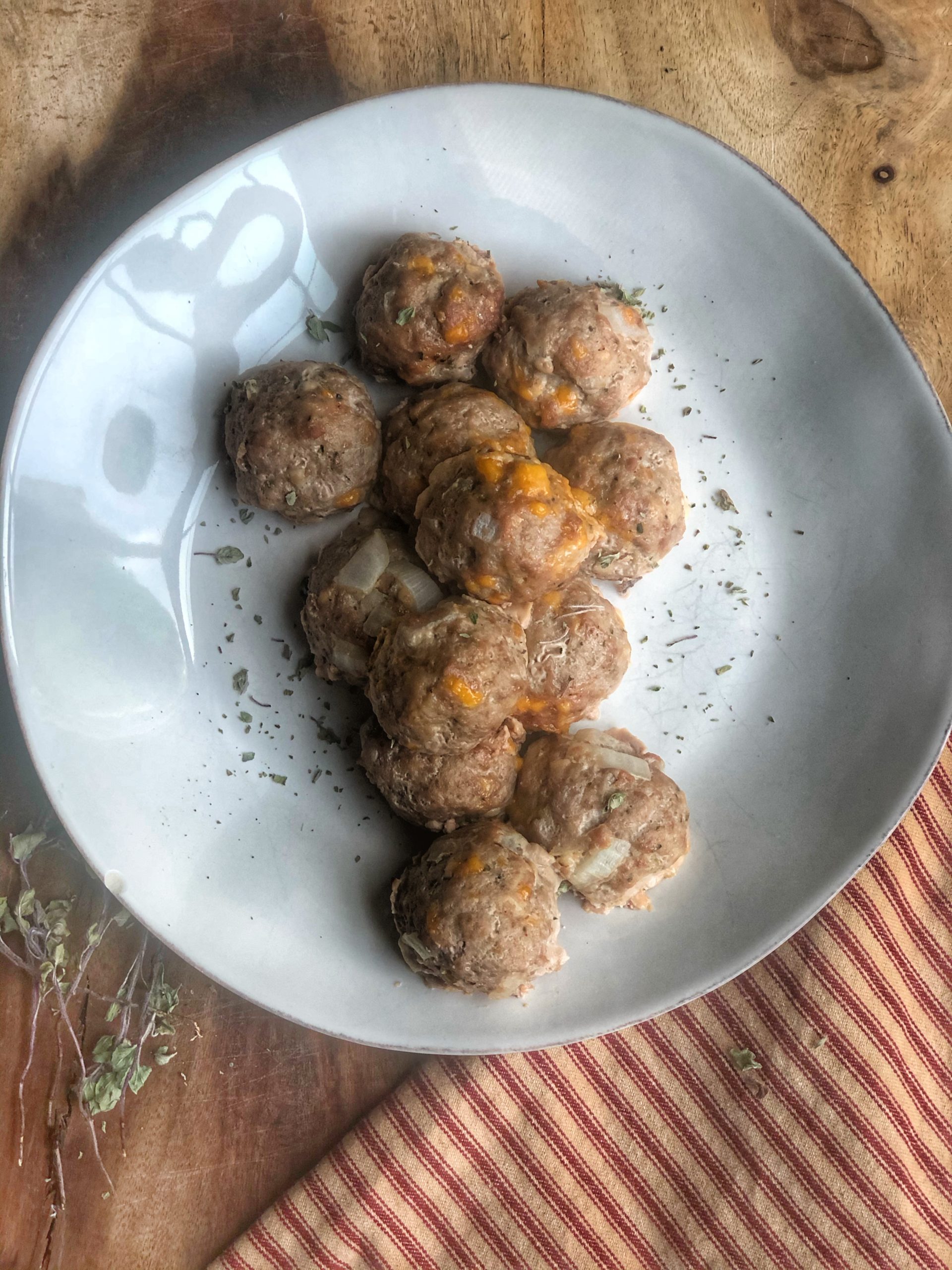 ground turkey cheesy meatballs on a white plate on a wooden board with a red and white striped napkin