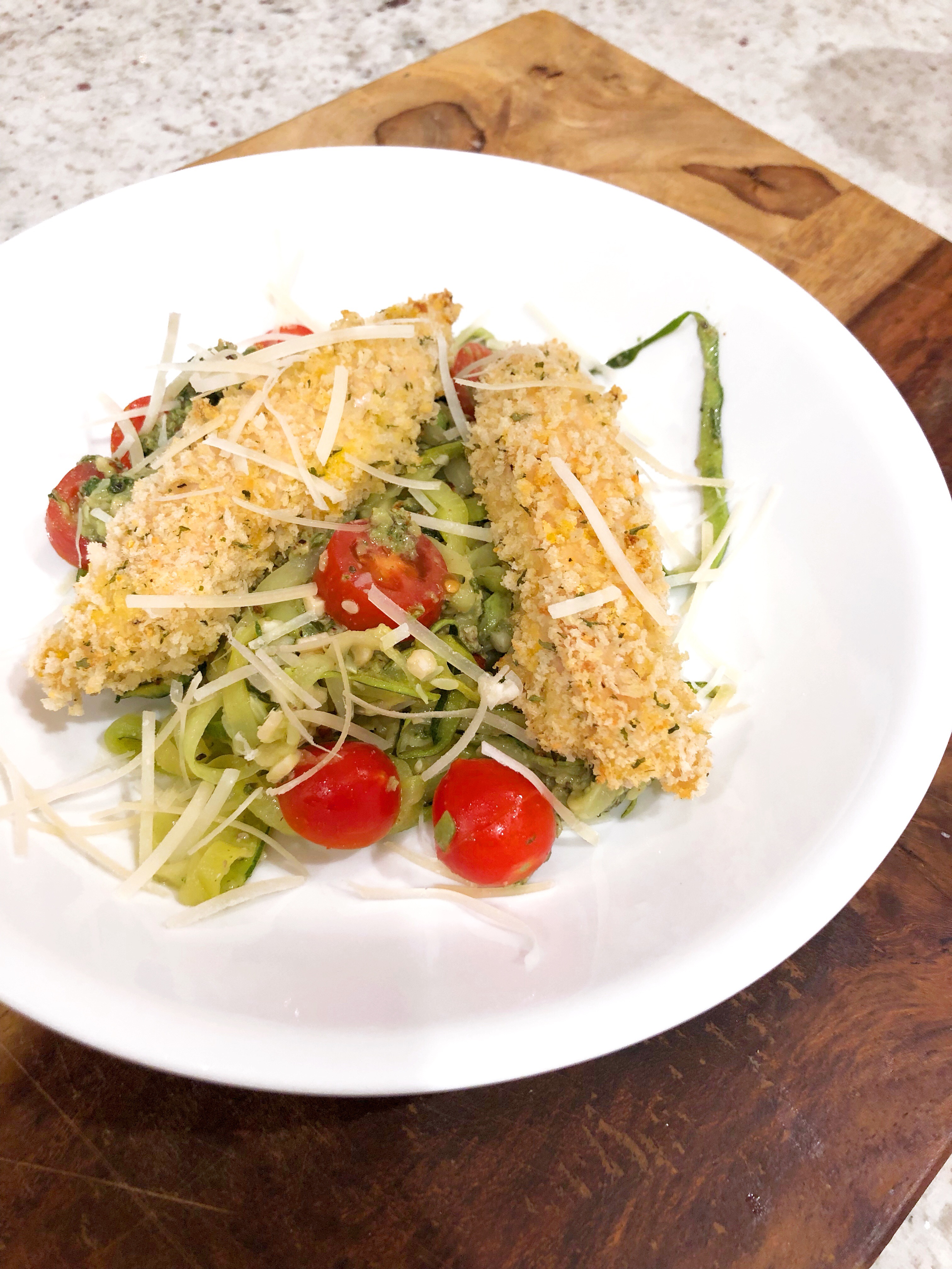 panko chicken over zoodles on a white plate