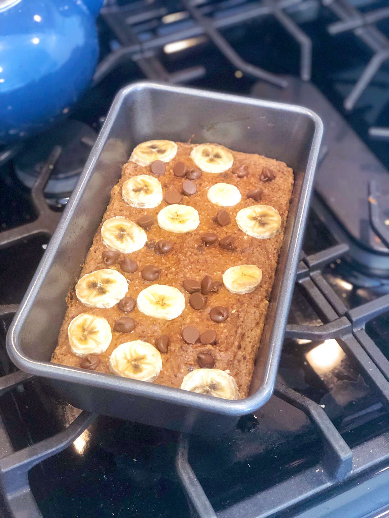 flourless banana bread on a wooden board with chocolate chips and banana slices on top