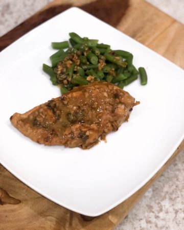 lemon garlic chicken on a white plate with string beans