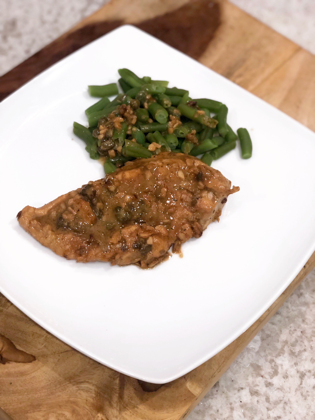 lemon garlic chicken on a white plate with string beans