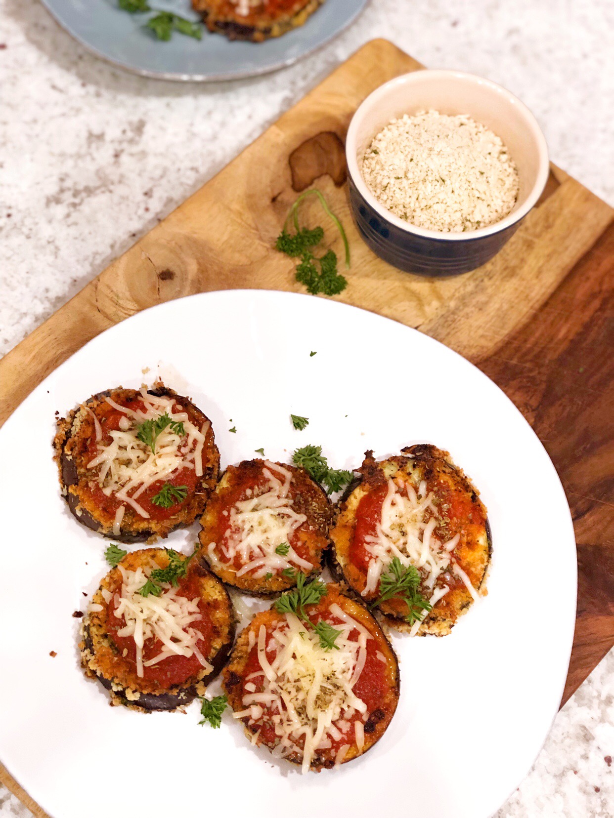 birds eye view of eggplant pizzas on a white plate on a wooden board