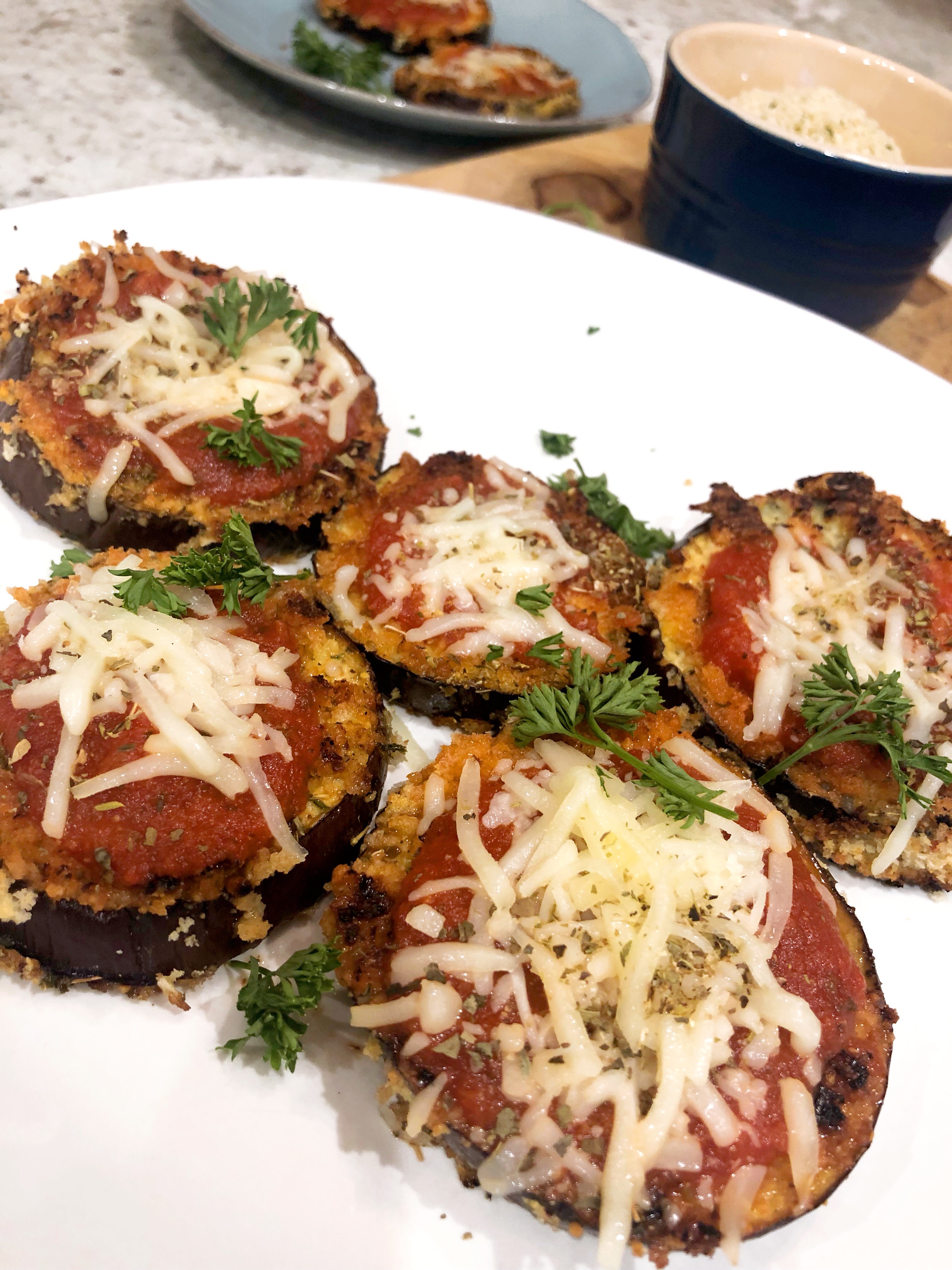 close up of eggplant pizzas on a white plate