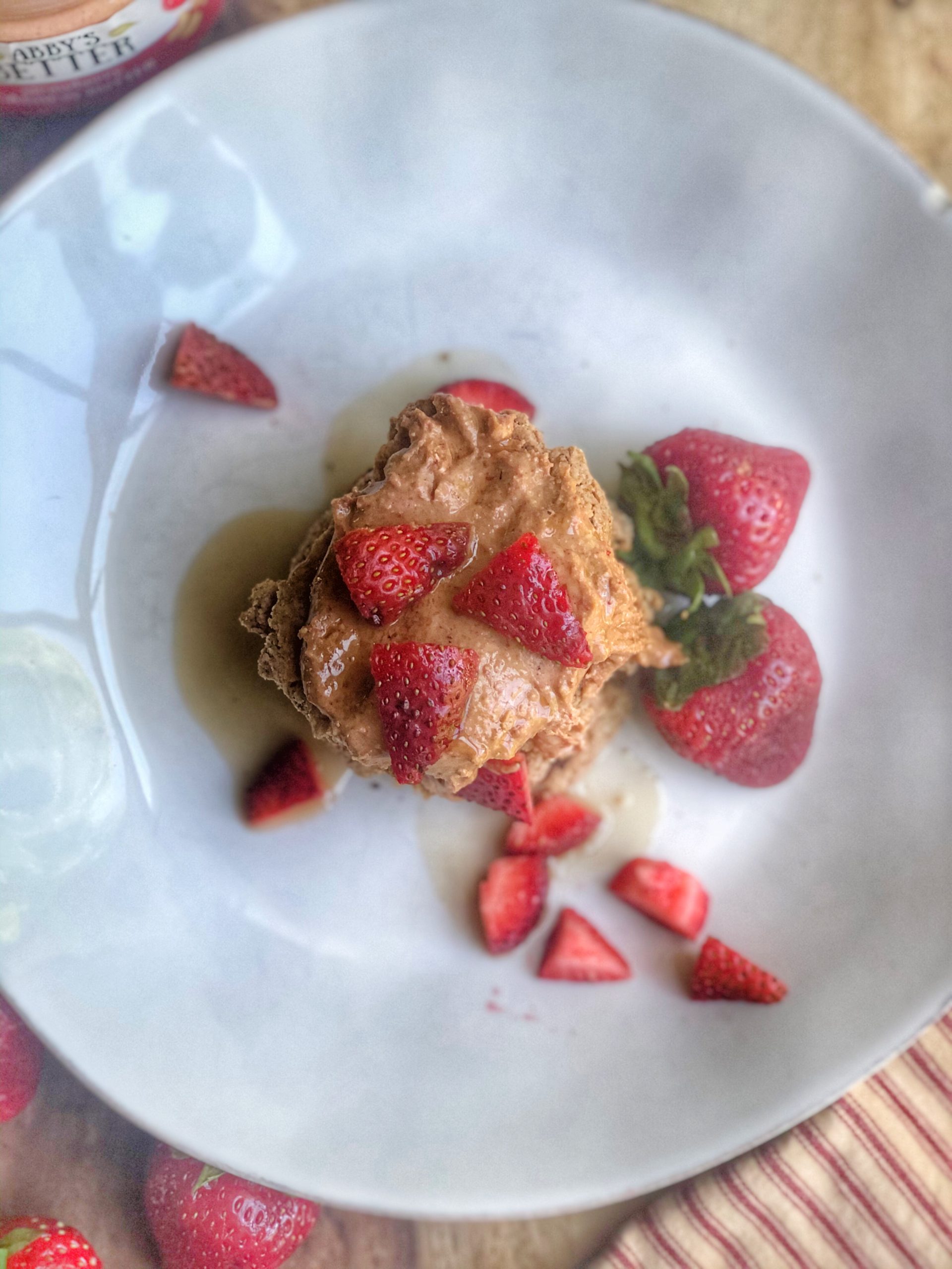 Abby's Strawberry Cashew Nut Butter pancakes on a white plate with some strawberries on the side.