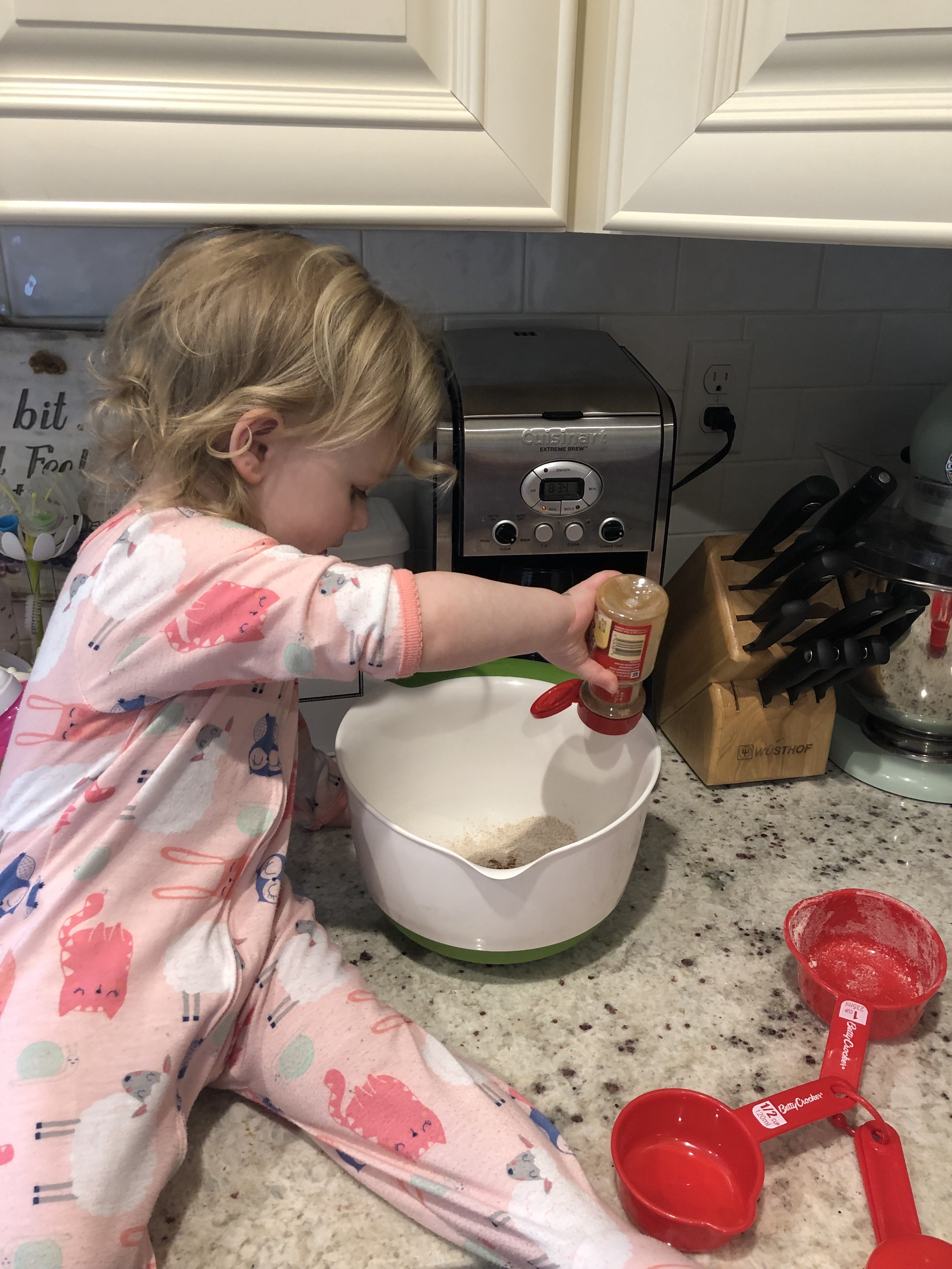 little blonde girl adding cinnamon to the pancake batter