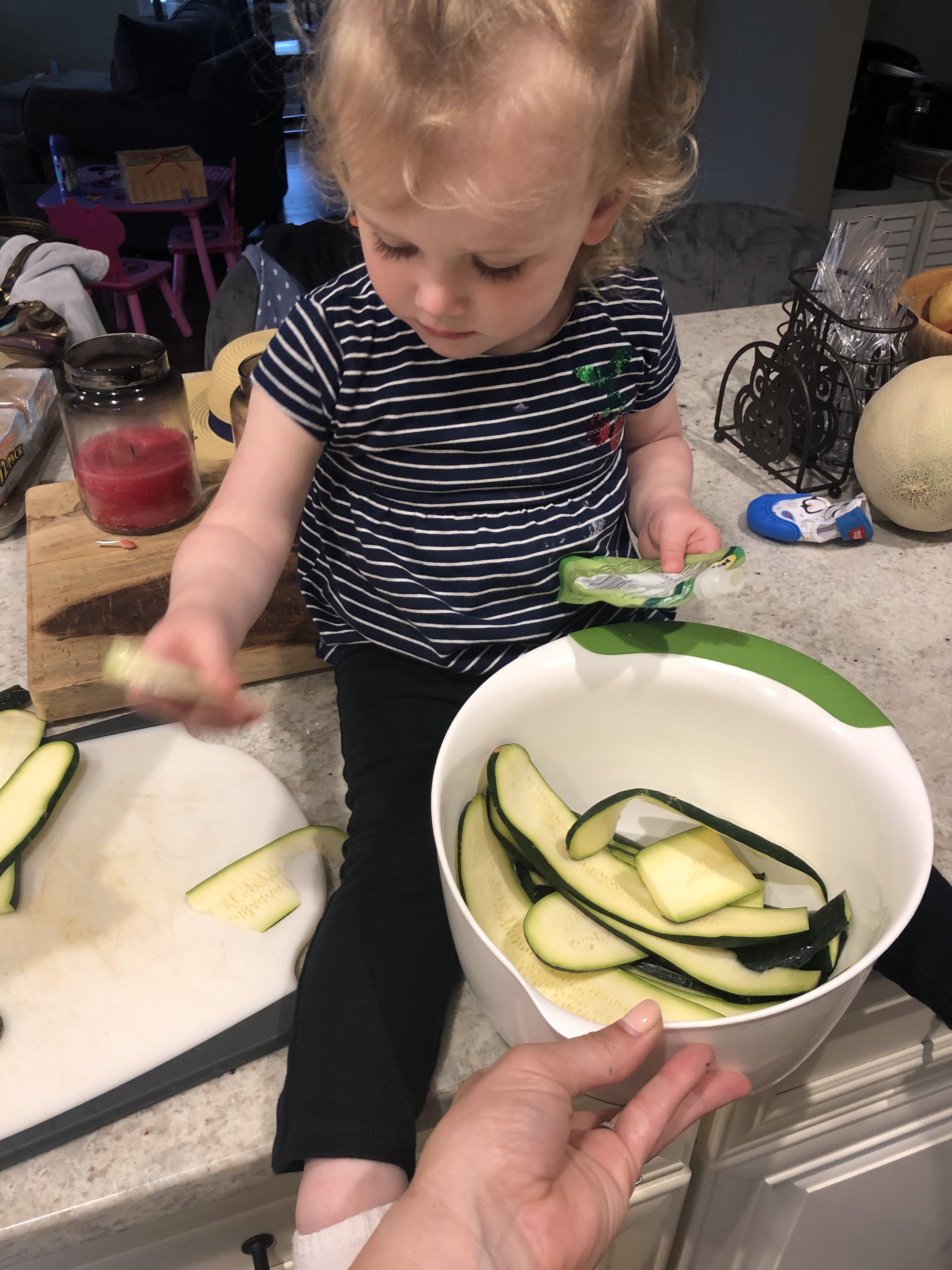little girl laying zucchini strips on a baking tray