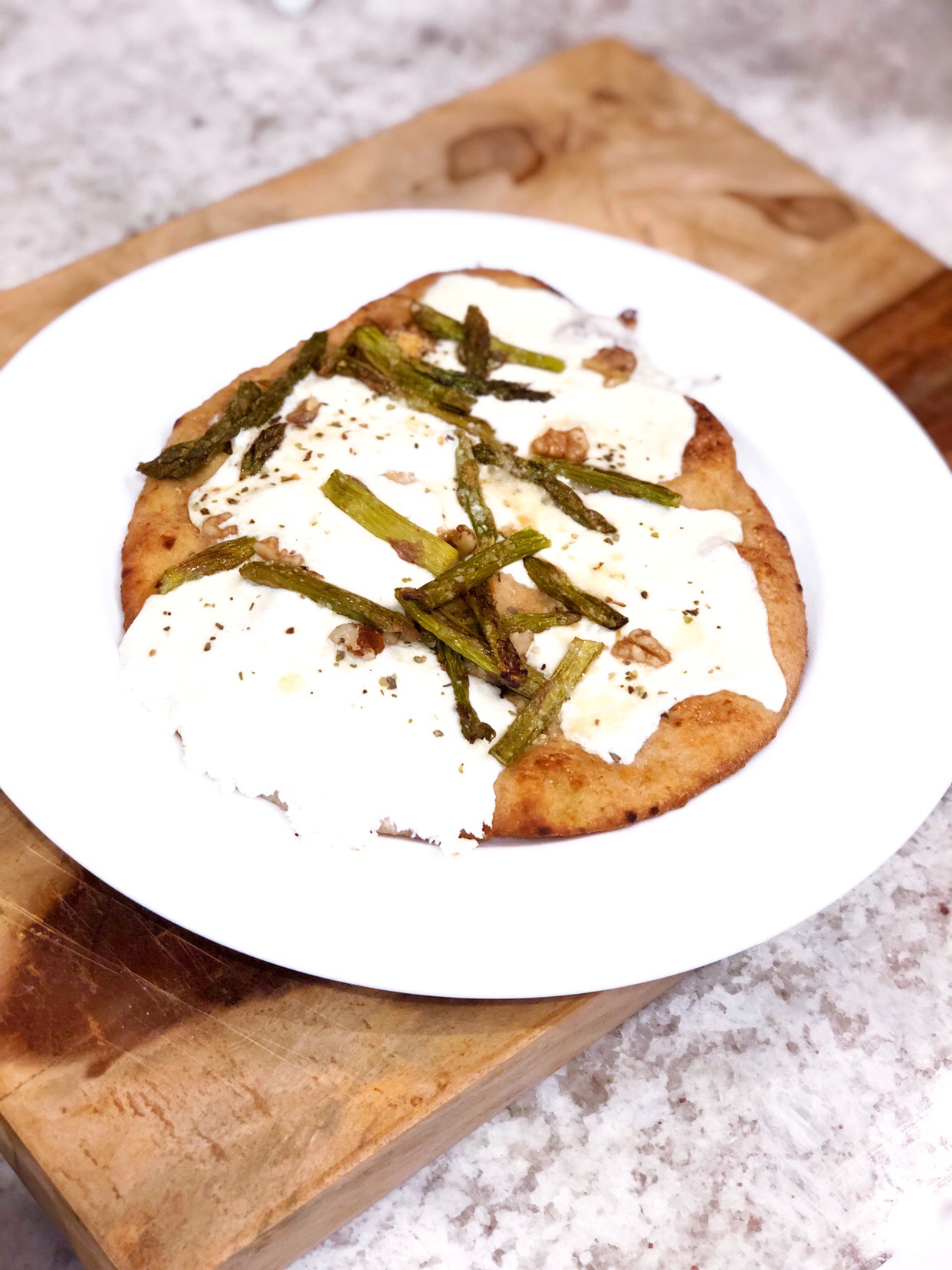 naan asparagus pizza on a white plate on a wooden board