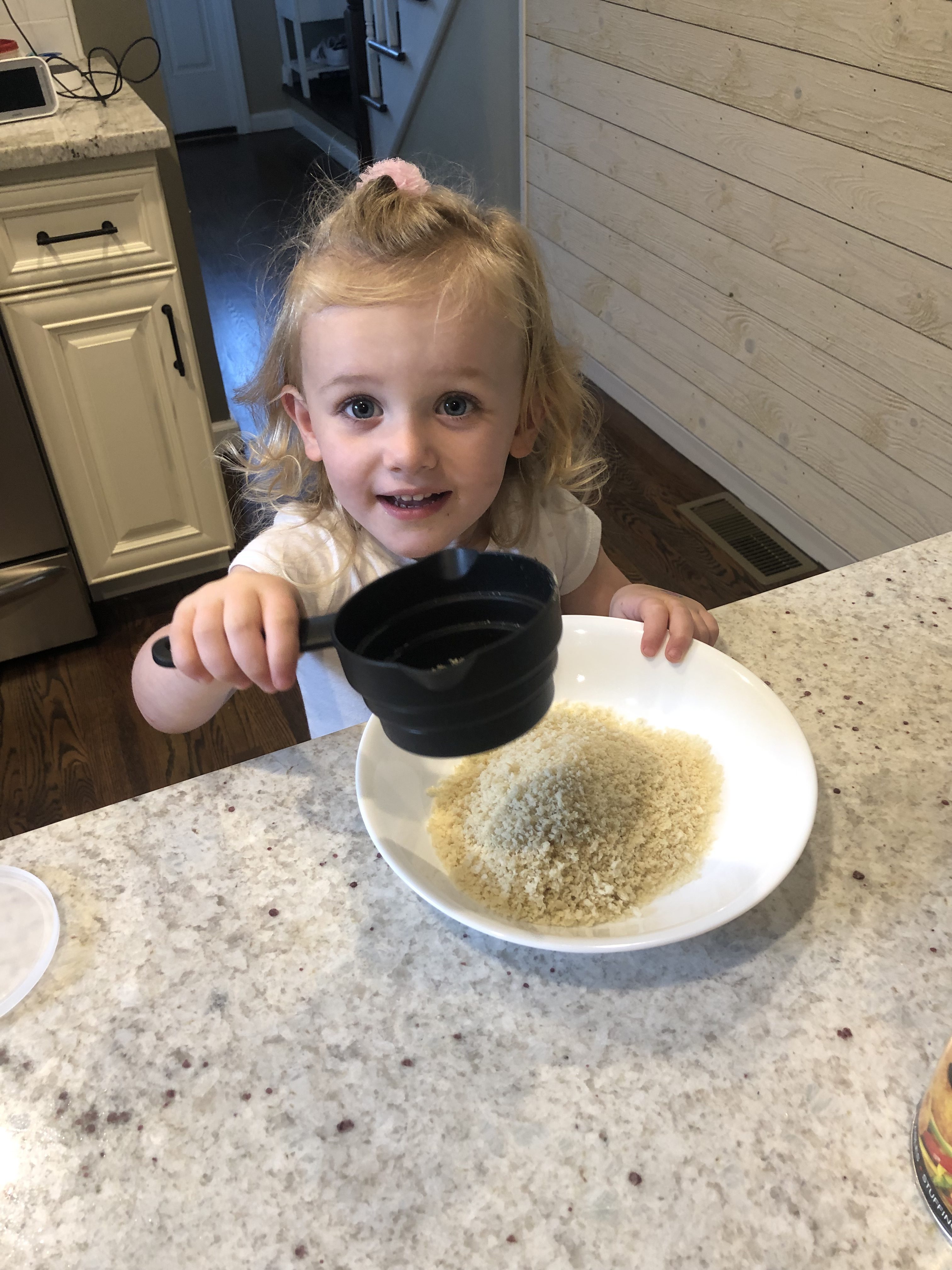 little blonde girl measuring out ingredients to make pork chops