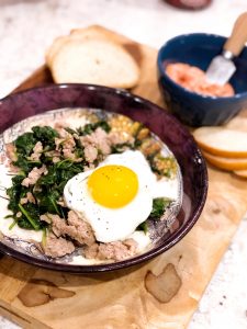 ground turkey, spinach, and an egg in a bowl on a cutting board