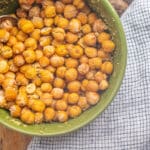 Chickpeas in a green bowl on a wooden table.