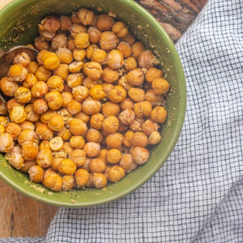 Birds eye view of roasted chickpeas in a green bowl on a wooden table.