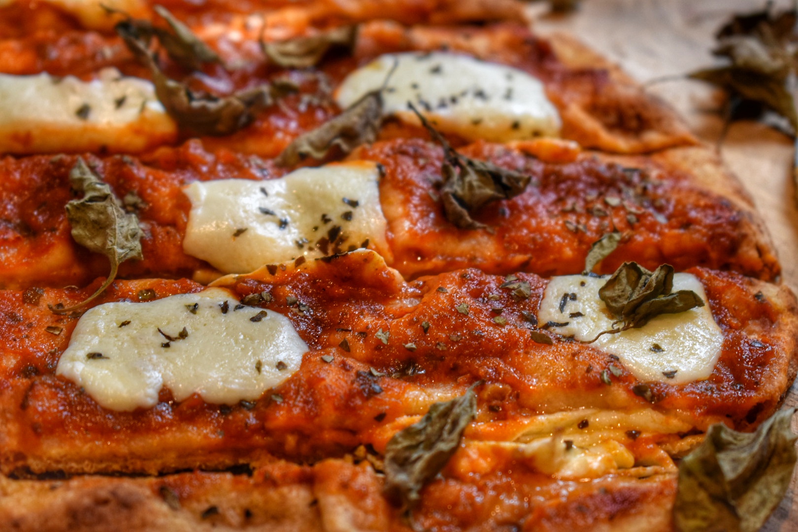 close up of crispy naan pizza with melted mozzarella cheese on tomato sauce topped with fresh basil