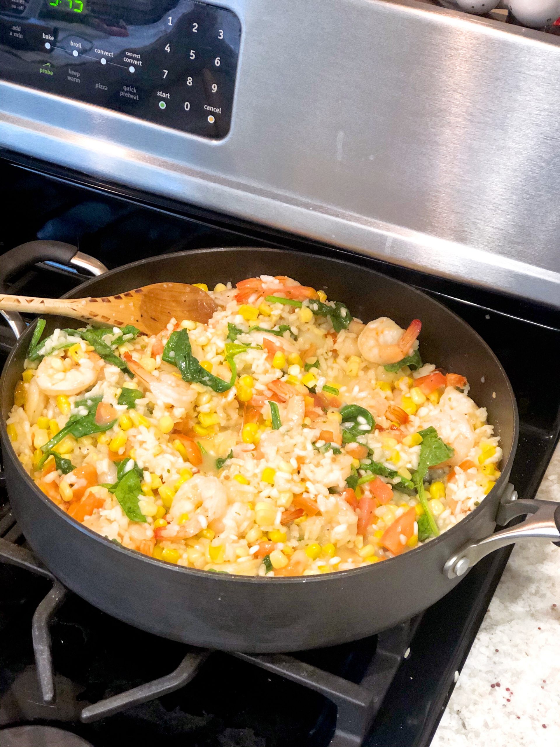 sweet corn risotto with sauteed shrimp in a deep skillet on the stove 