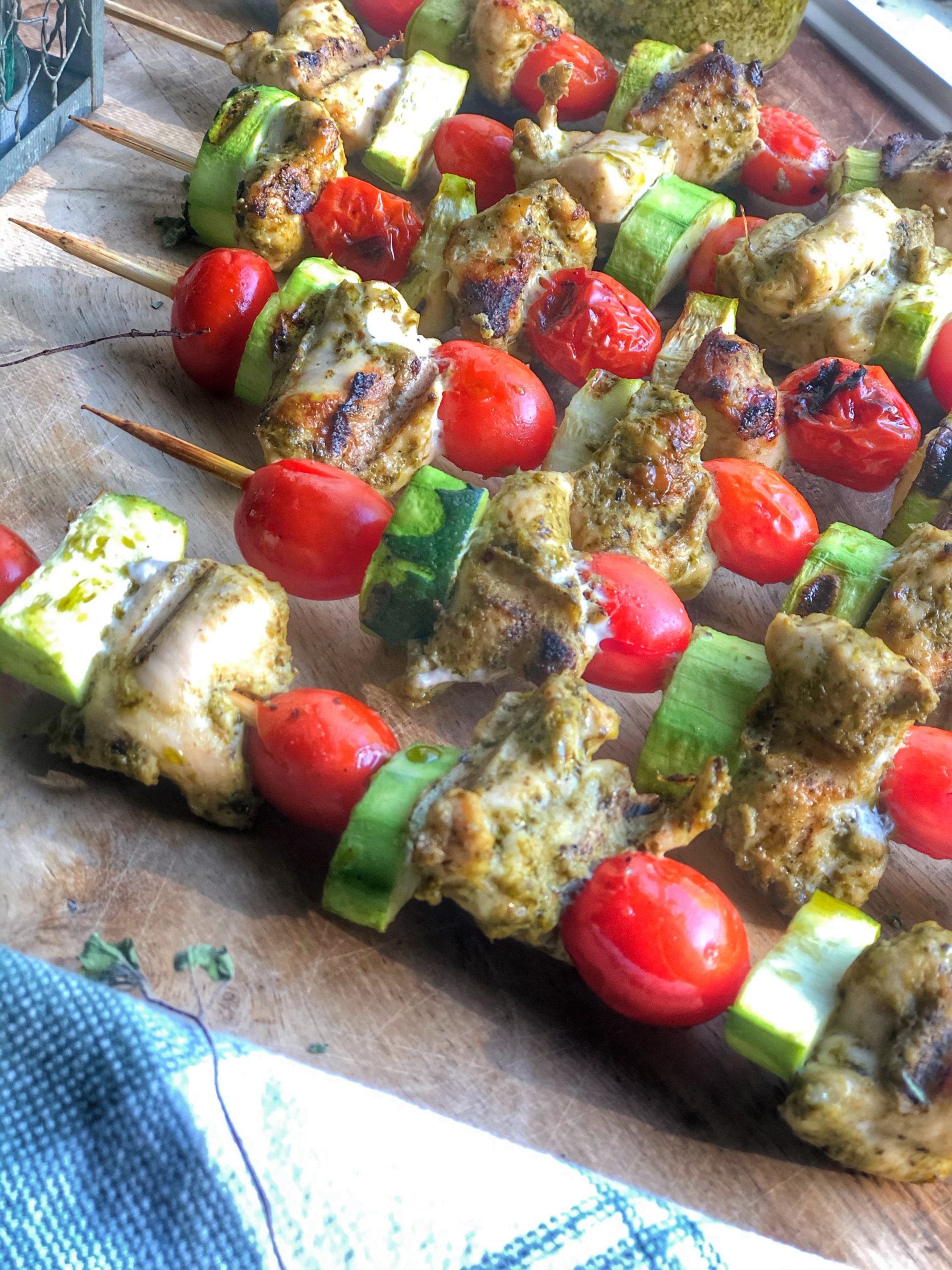 close up of grilled chicken pesto skewers on a wooden board