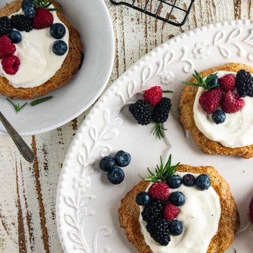 3 almond cookies topped with whipped cream and fresh berris.