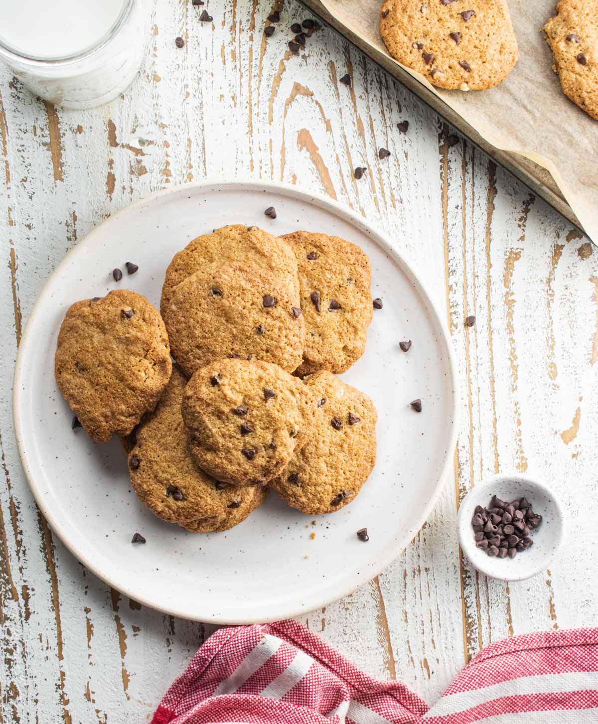 almond flour chocolate chip cookies without butter on a white plate sitting on a white board with a red and white stripped cloth napkin