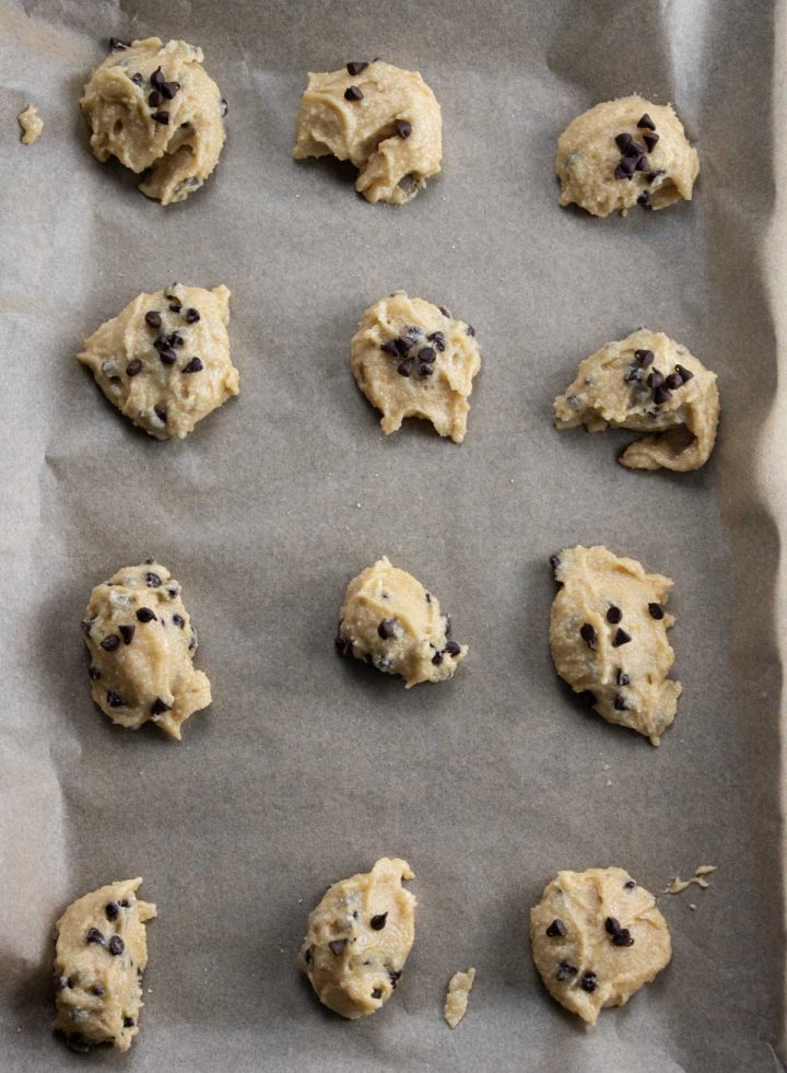 scoops of cookie dough on a baking sheet lined with cookie dough