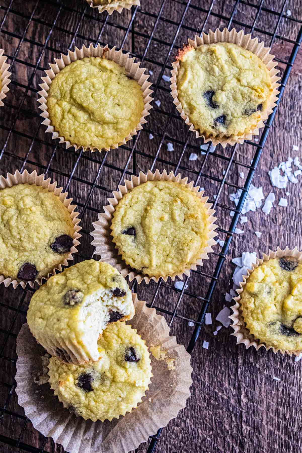 A birds-eye view of coconut flour muffins on a cooling rack with scattered coconut flakes.