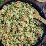 Creamy chicken orzo in a cast iron skillet with a wooden spoon slotted in the side.