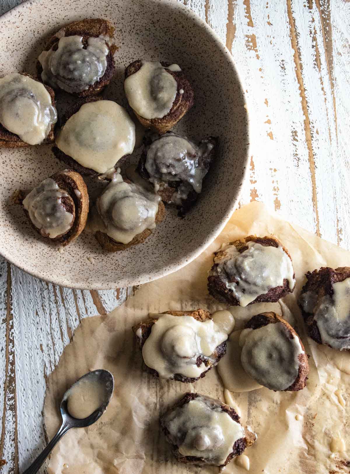 birds eye view of crockpot cinnamon rolls on a slice of parchment paper and in a cream colored bowl