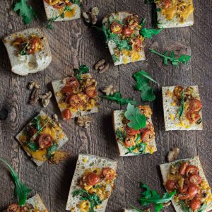 birds eye view of easy cheese crostini appetizer on a wooden board with scattered walnuts and cilantro