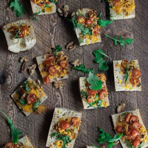 birds eye view of easy cheese crostini appetizer on a wooden board with scattered walnuts and cilantro