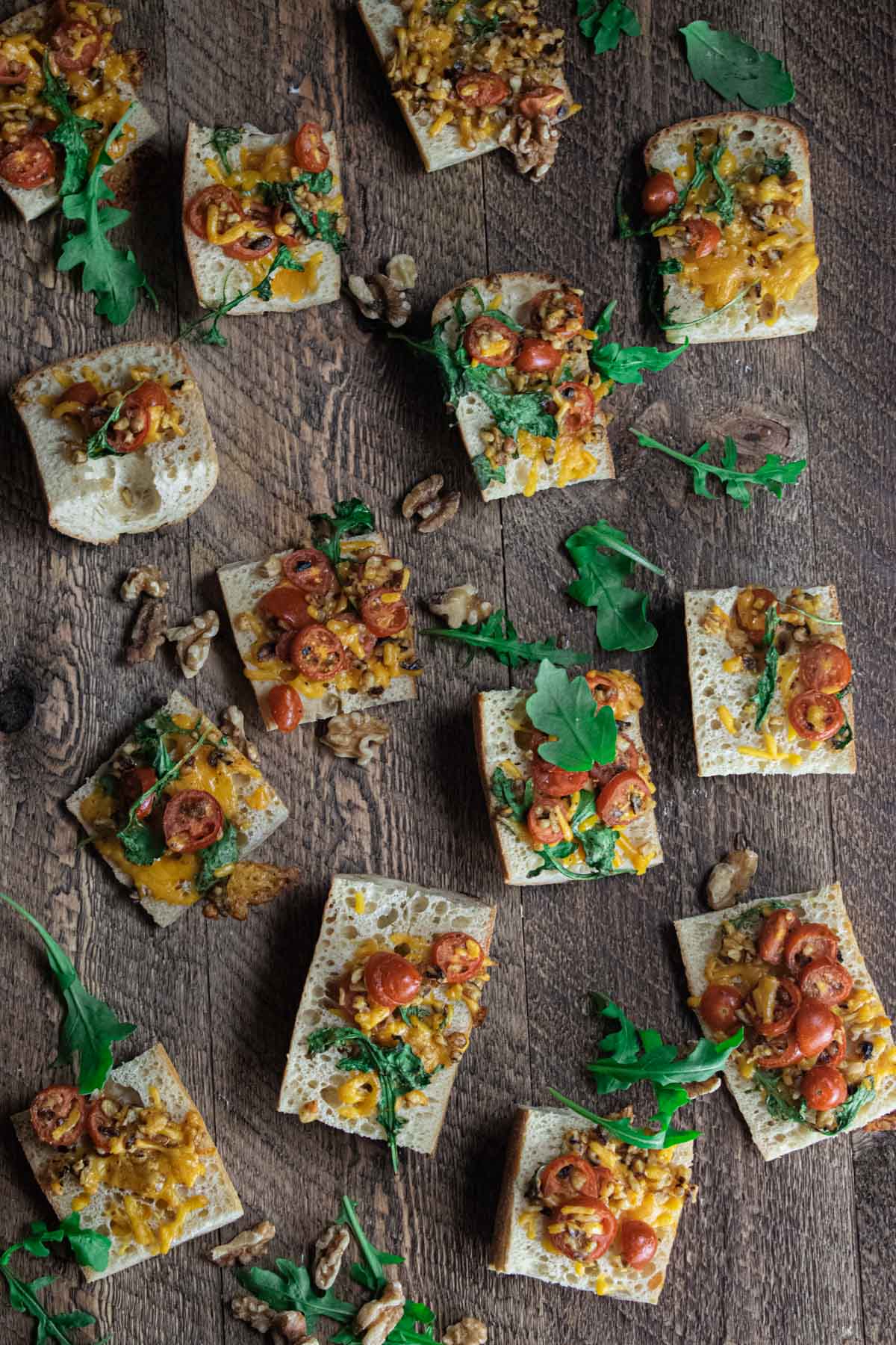 birds eye view of easy cheese crostini appetizer on a wooden board with scattered walnuts and cilantro